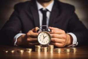 Man in suit with stacks of coins and alarm clock - A CDFA can save you time and money.