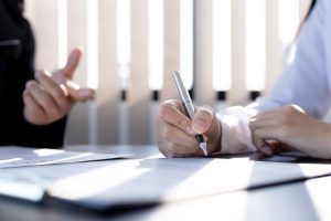Two people sit at a desk discussing finance and important money matters.