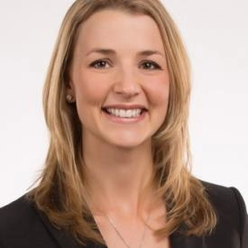 A woman with blonde hair, wearing a black blazer and a necklace, smiles at the camera against a plain white background, reflecting the confidence of an experienced divorce financial planner.